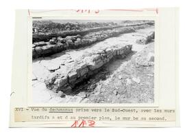 XVI.- Vue du decumanus prise vers le Sud-Ouest, avec les murs tardifs a et d'au premier plan, le ...
